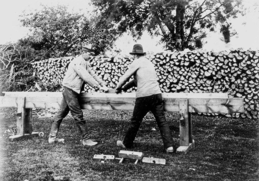 Foto av fogbänk på Gotland. Billedteksten frå fotoarkivet: Plank hyvlas med oxhyvel. Planken är fastspänd i en "fogbänk". Gotland Burs 1908. Foto: Nordiska museet 372 oai. På kanten av fotografiet står M. Klintberg fot. 