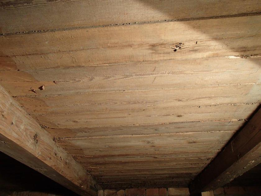 Undersida av golvet med laus fjør. Spora tyder på at det er saga på ei oppgangssag/rammesag. Borda er lagt med marg opp og er hogd til på tjukna for å ligge på åsane. Foto: Magnus Wammen